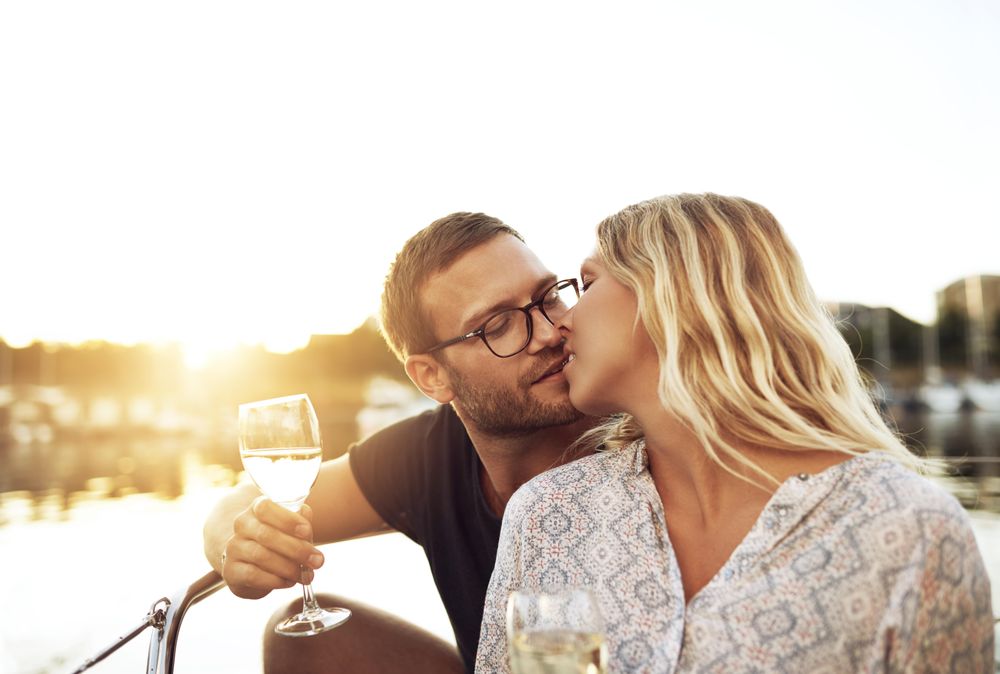 Couple kissing on a boat with wine glasses