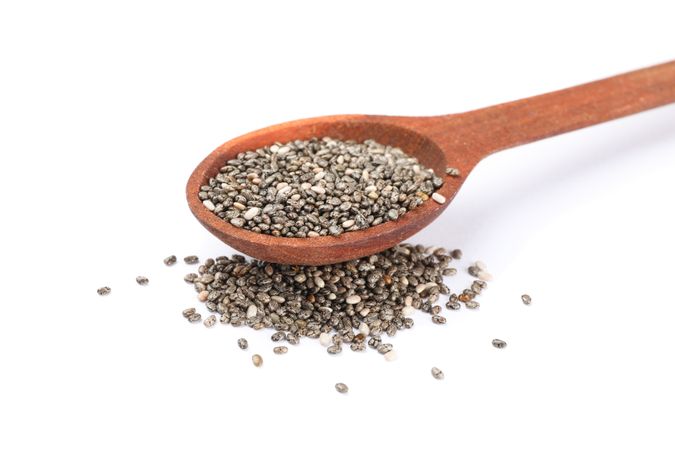 Chia seeds and wooden spoon isolated on blank background
