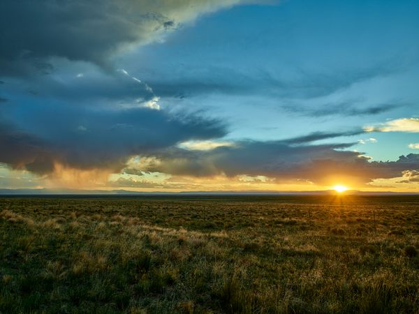 Sun setting with orange rays over flat Colorado fields