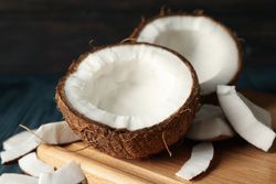 Board with coconut on wooden background, close up