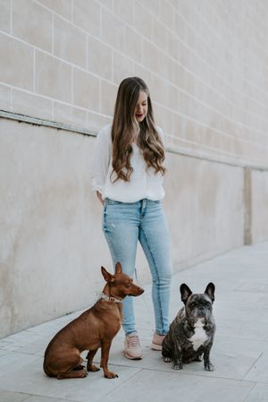 Stylish woman with dogs standing on street