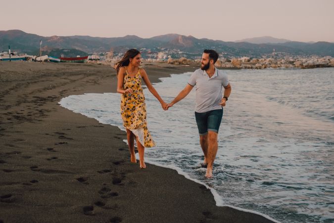 Lovely couple walking holding hands on sandy beach