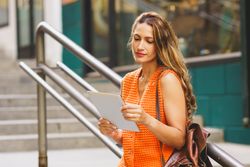 Woman reading tablet on stairs outside