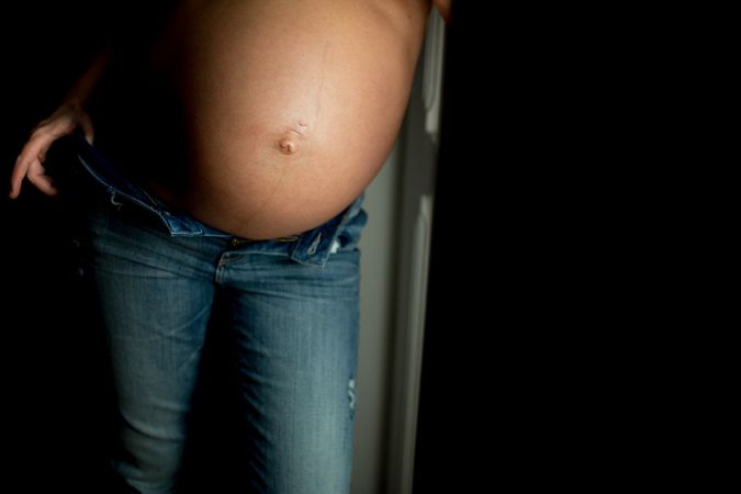 Crop pregnant woman near open door