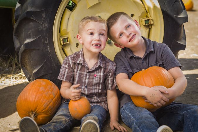 Two Little Boys Having Fun at the Pumpkin Patch on a Fall Day.
