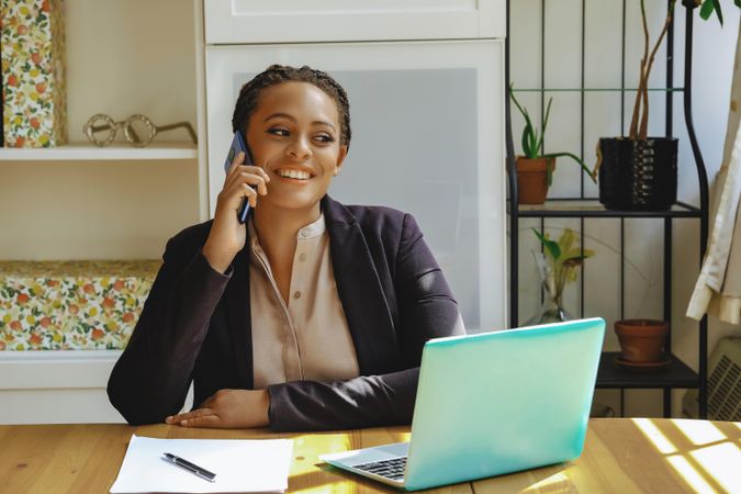 Smiling female business owner taking phone call in her home office