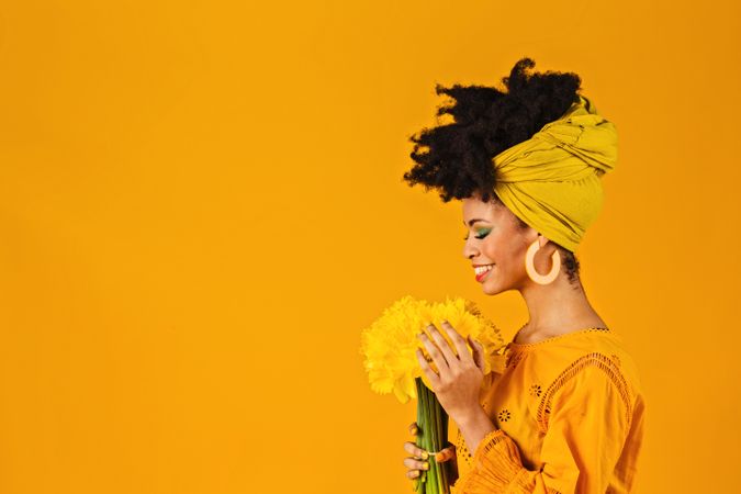 Portrait of happy Black woman smiling at a bouquet of daffodils