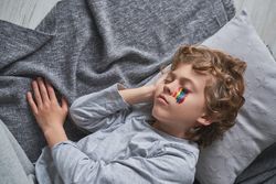 Calm kid with rainbow under eye sleeping on floor