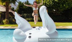 Cheerful woman jumping on inflatable toy in swimming pool 5RoP14