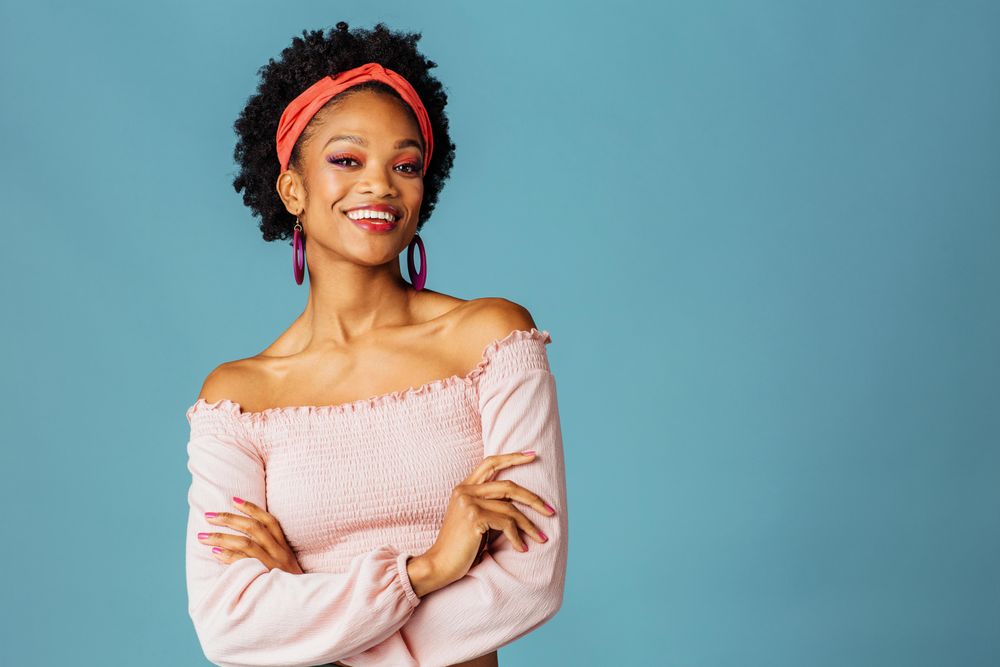 Studio shoot of happy Black woman with her arms crossed