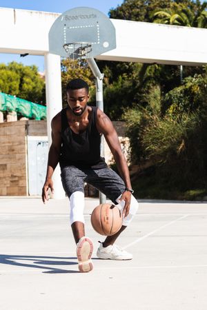 Black man playing basketball on sports ground