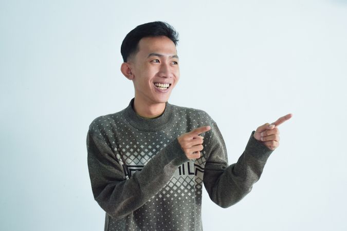 Asian young man pointing to his side