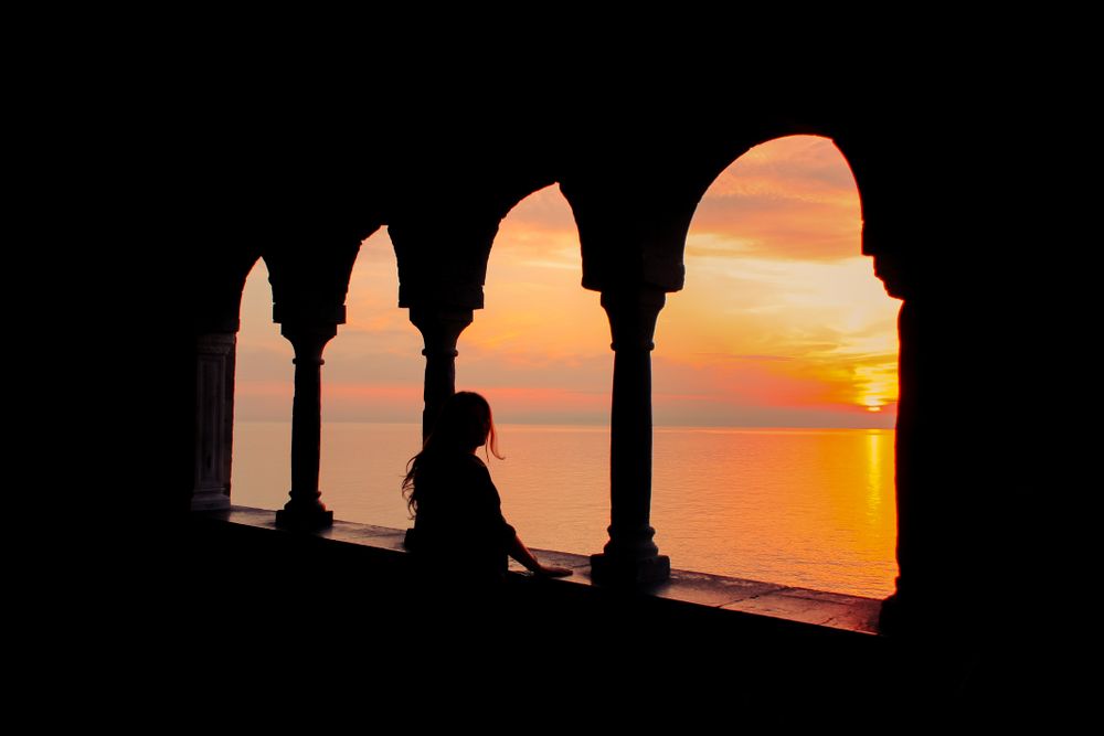 Silhouette of woman standing in building looking at sunset
