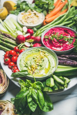 Fresh colorful vegetables and dips with hummus, avocados, asparagus, carrots, close up of green dip