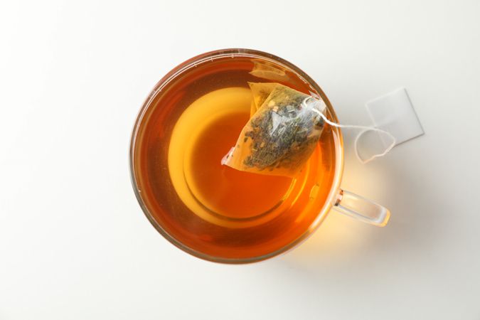 Cup of tea with tea bag on plain background, top view