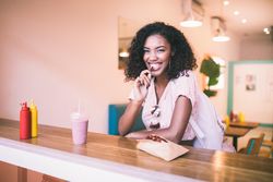 Young woman playfully taking a bite of a French fry at a restaurant counter