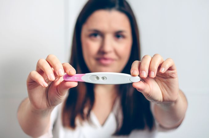 Pregnant woman showing pregnancy test