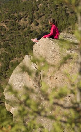 Young female sitting on cliff