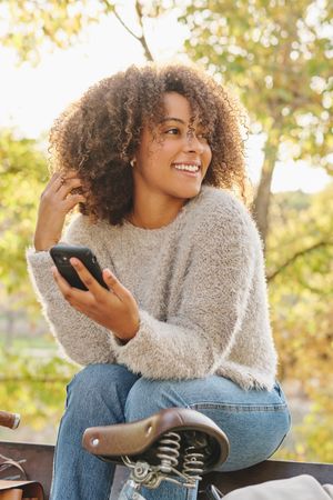 Smiling Black woman using smartphone in park