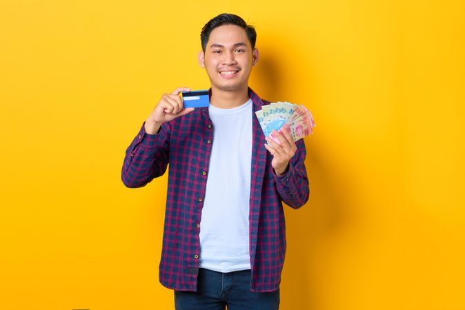 Man holding up credit card and cash