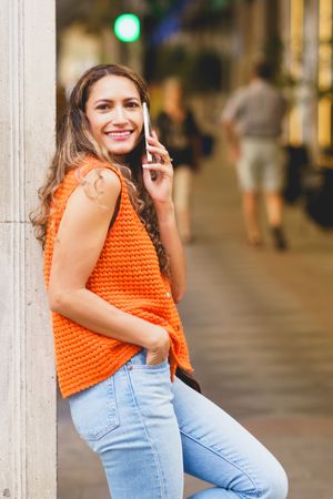 Woman leaning on a facade talking to the mobile