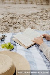 Cropped image of a person reading a book on the beach bY7N65
