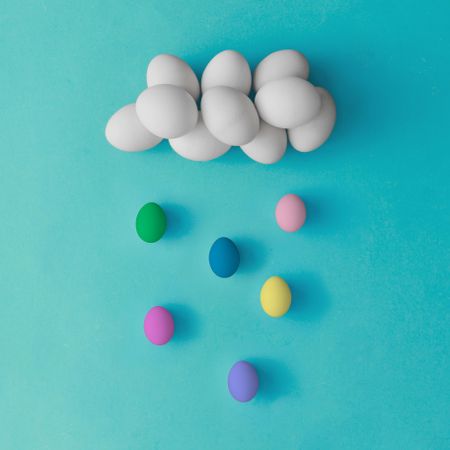 Cloud and rain made of colorful Easter eggs on blue background