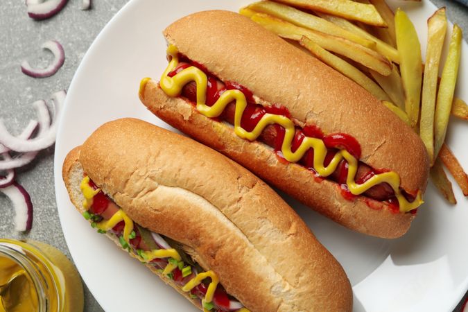 Tasty hot dogs and fries potato on gray table, top view