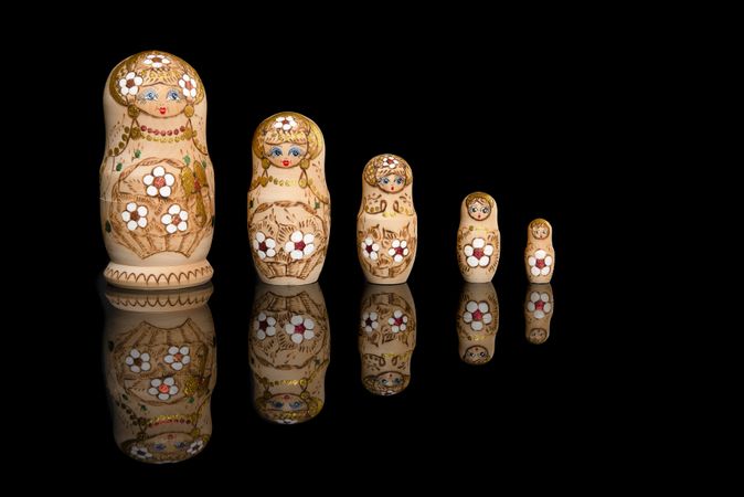 Wooden Russia matrioshka dolls in a row on a reflective dark background