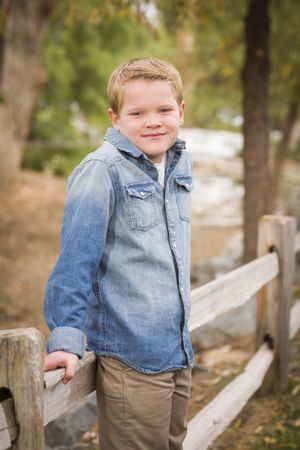 Handsome Young Boy Against Fence in Park