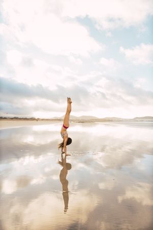 Woman doing handstand near sea
