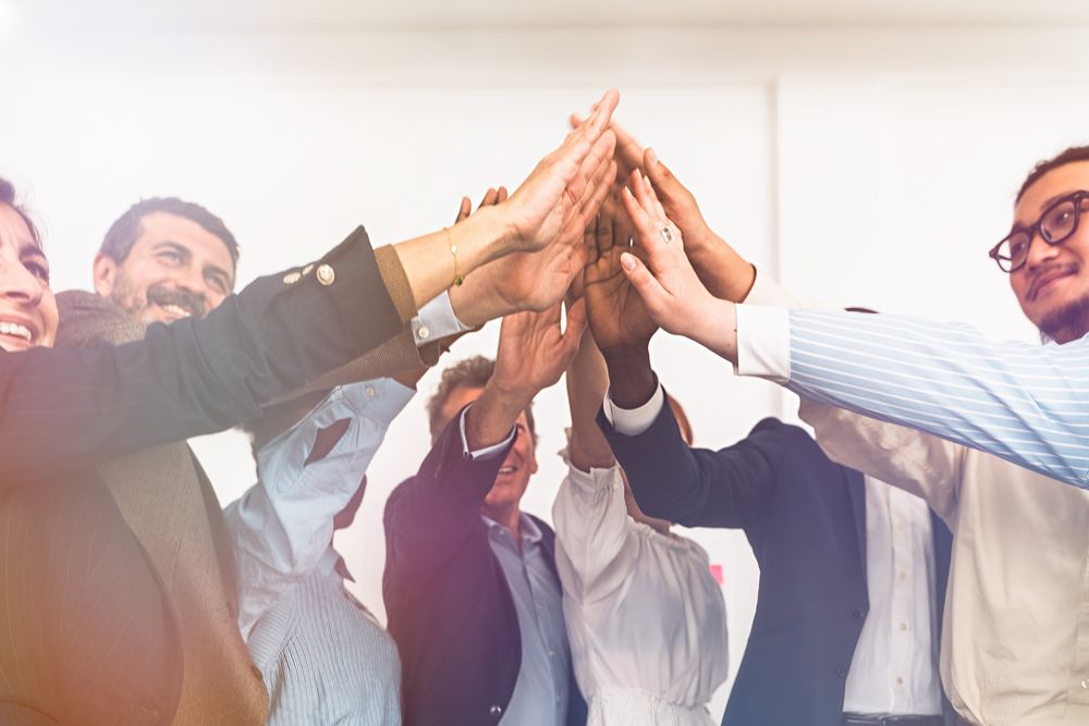 Enthusiastic team of diverse professionals doing a high five in office celebration of success