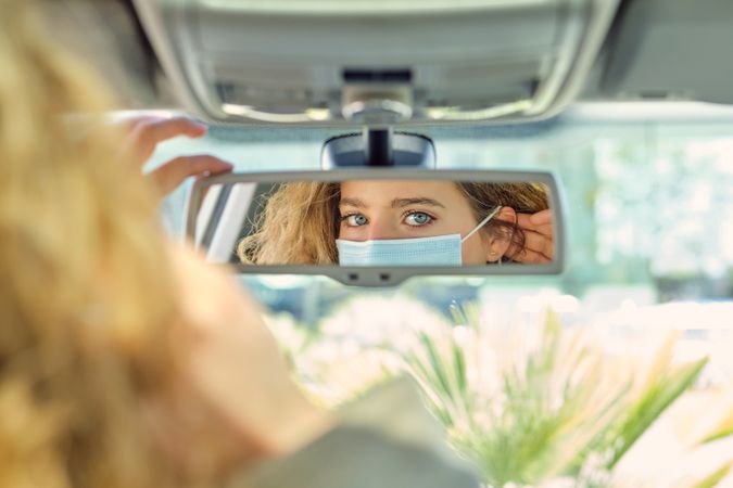 Crop woman putting on respiratory mask in car