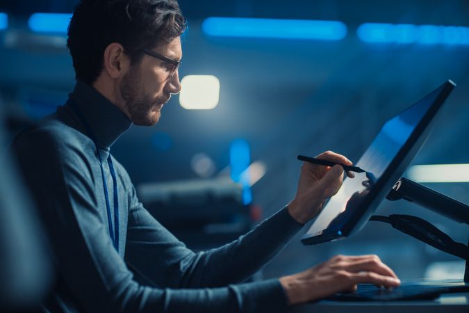 Professional Automotive Graphic Designer is Working on Concept Car Render with a Stylus Pen in a High Tech Innovative Laboratory with a Prototype Car Chassis.