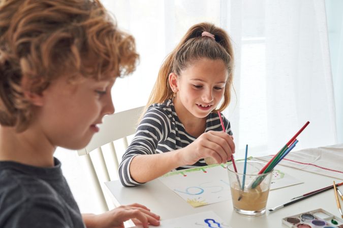 Cute siblings painting together at table