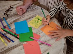 Unrecognizable kid drawing near grandparent