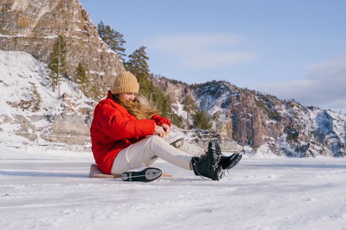 Woman sitting on snow and changing boots