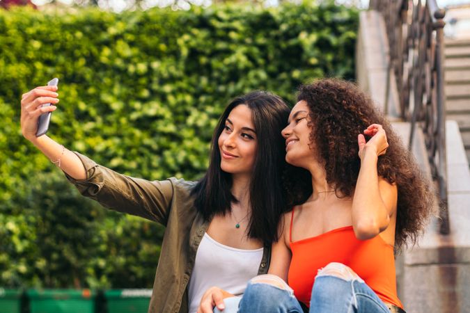 two women sitting on a stairs taking a selfie