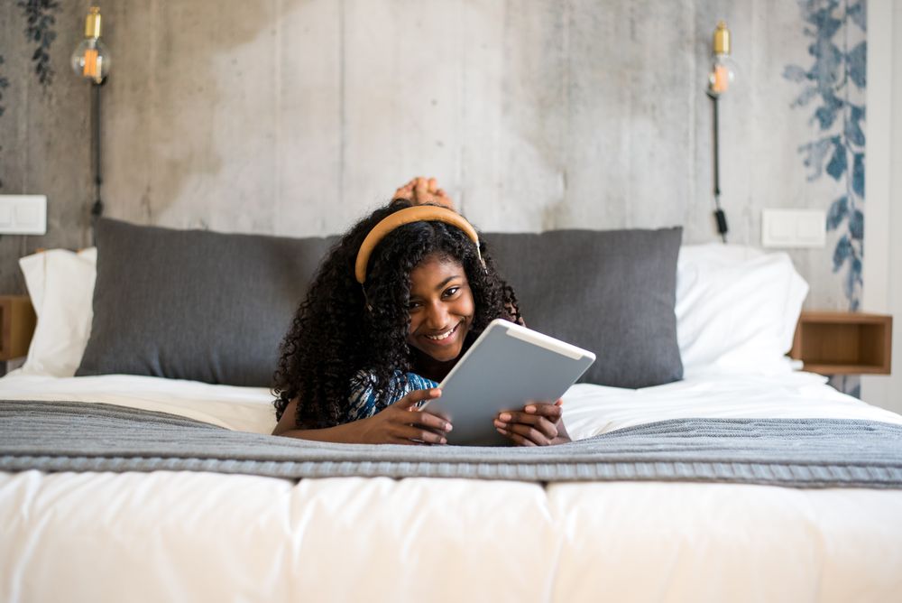 Black girl using tablet in bed