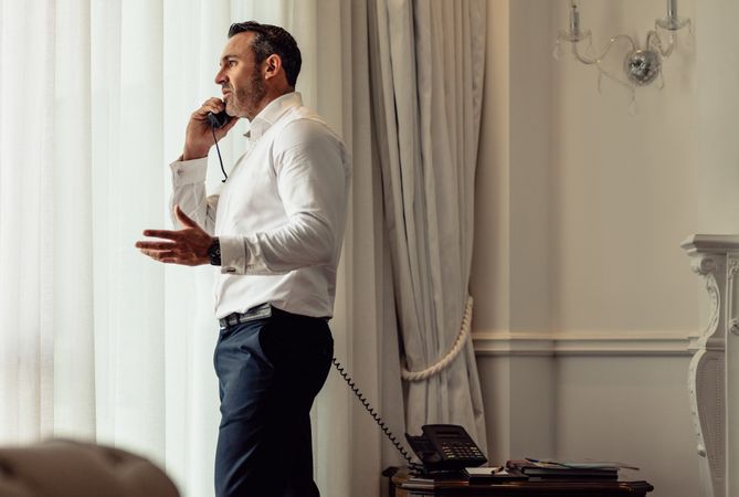 Man on business trip talking on hotel room phone