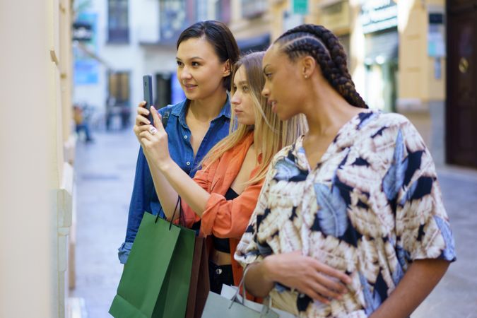 Women taking photo with phone of store window