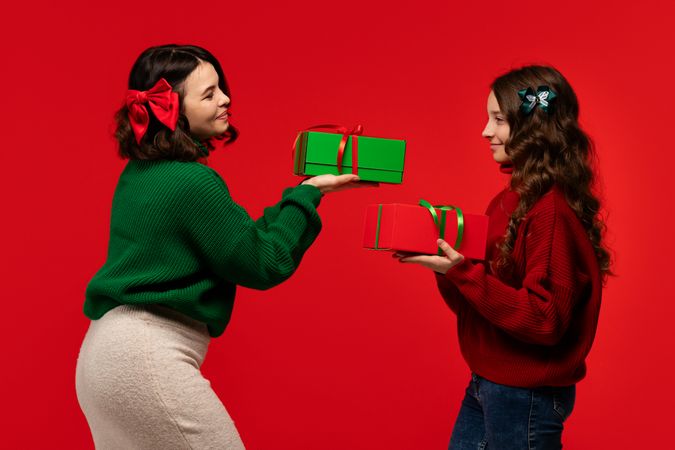 Mum and teenage daughter share red and green boxes, smiling