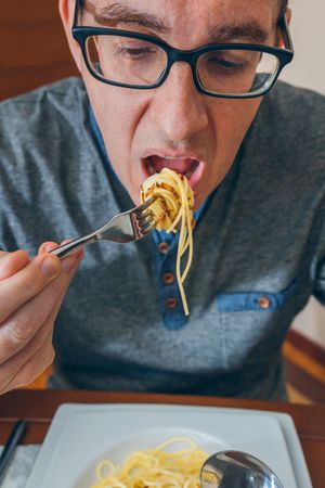 Man eating spaghetti with worms