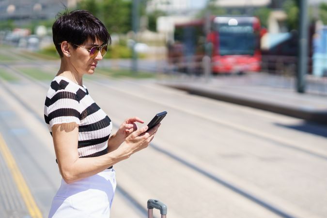 Female checking phone while waiting for train