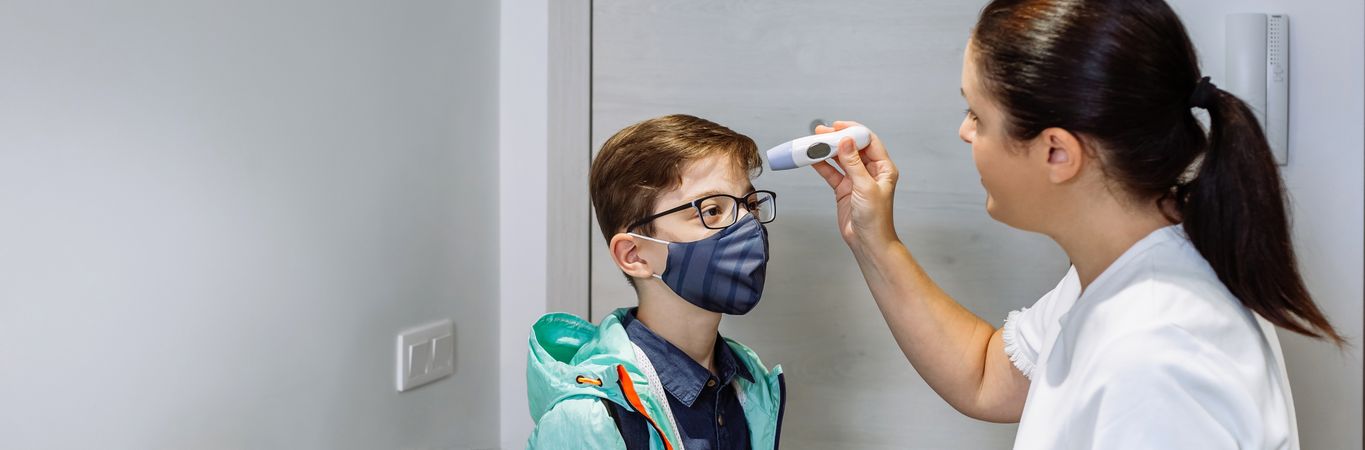 Mother checking her son's temperature before going to school