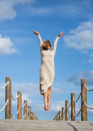 Young woman jumping and posing on footbridge