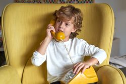 Interested boy speaking on old fashioned wired phone