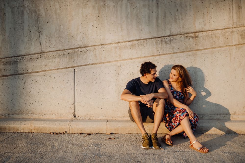 man and woman sitting at nearby street wall