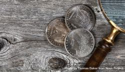 Morgan silver dollars with magnify glass on wood 4BGXMb