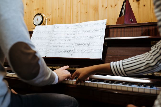 Man playing piano near woman teaching in studio